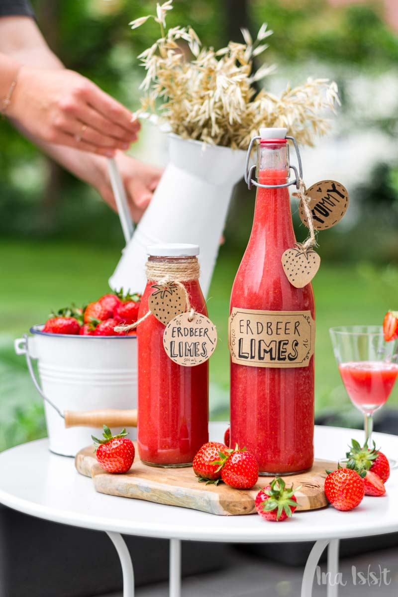 Erdbeer Limes Rezept in Flaschen auf Gartentisch im Grünen, Erdbeer Limes selbermachen, #erdbeerlimes
